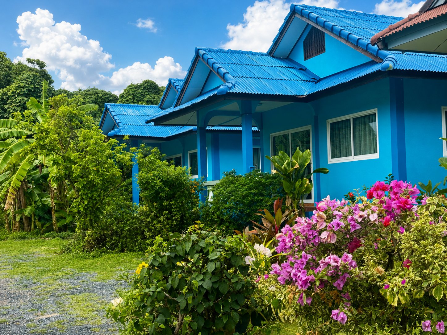 Row of blue Thai bungalows surrounded by tropical greenery and flowers on Koh Samui